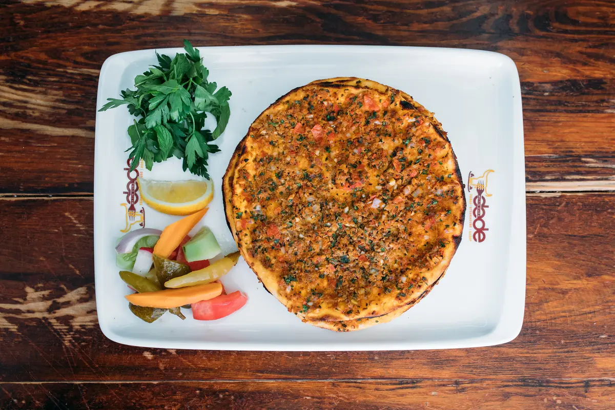 Dede Kebap'ın Adana usul&uuml; lahmacunu &uuml;stten: yuvarlak hamur, kuzu kıymalı har&ccedil;