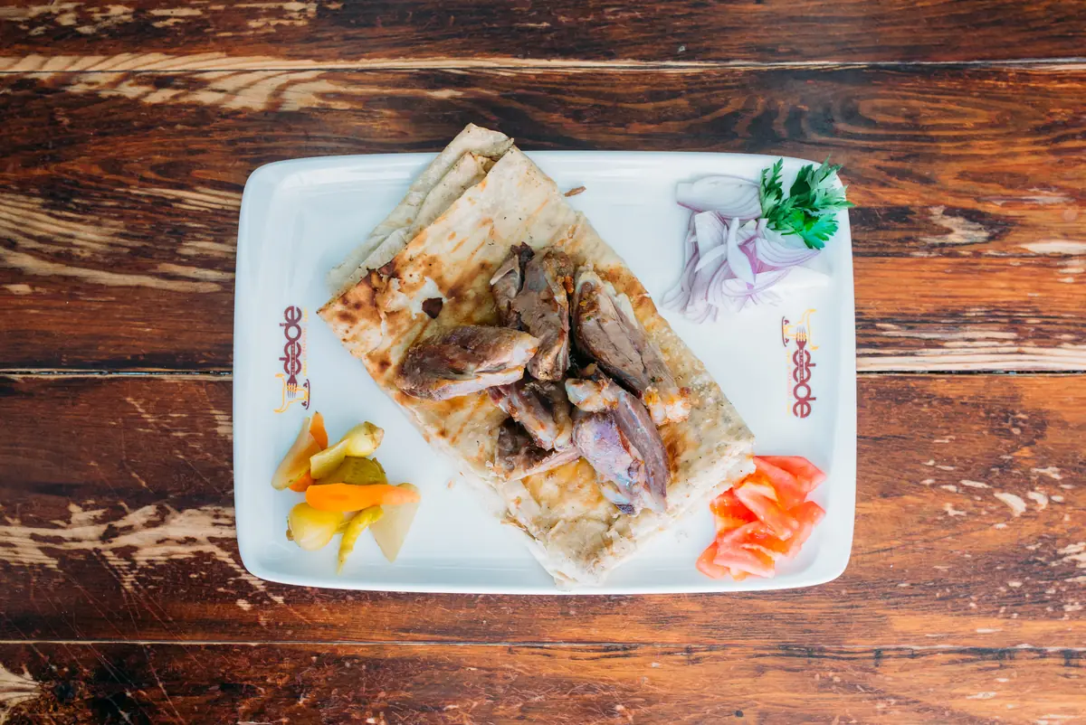 Dede Kebap'ta b&uuml;ryan servis tabağı: yufka &uuml;zerinde b&uuml;ryan, soğan ve turşu