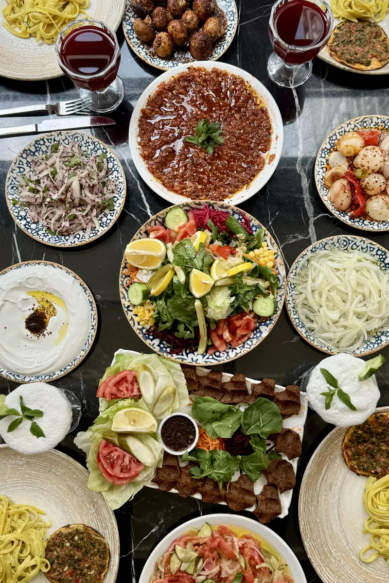 Dede Kebap'ta ana yemekle masaya gelen mezeler ve ikramlar: mevsim salata, soğan salatası, s&uuml;zme yoğurt, makarna, fındık lahmacun ve &ccedil;iğ k&ouml;fte