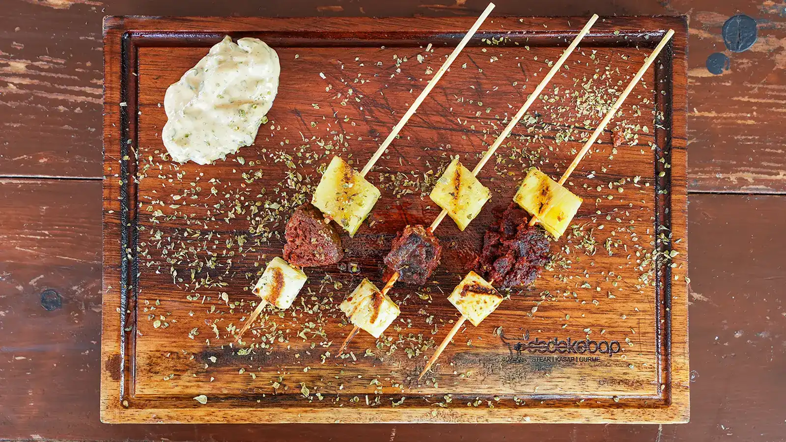 Özel Aşk Üçgeni, köz ateşinde pişirilmiş sucuk, ızgara peynir ve ananas dilimlerinden oluşan şiş sunumu, yanında özel sos ile – Adana Dede Kebap Steak Burger Tatlı Kasap