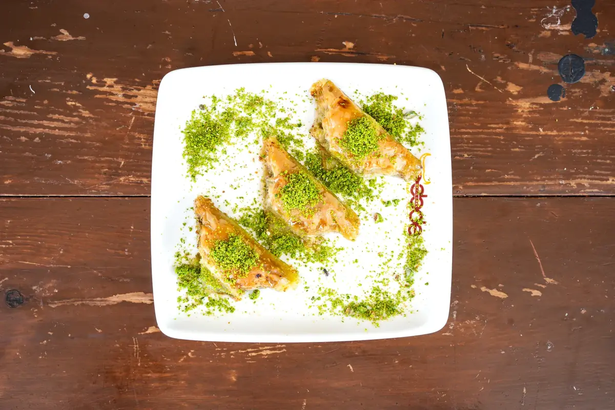 Dede Kebap'ta ş&ouml;biyet: &uuml;&ccedil;gen katlanmış, &uuml;zerine toz Antep fıstığı serpilmiş kaymaklı baklava