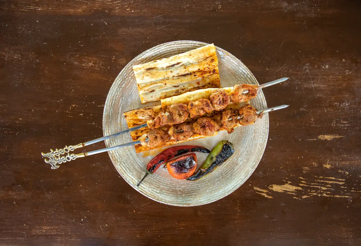 Dede Kebap'ta pide &uuml;zerinde iki şiş kuzu yağlı kara kebabı, k&ouml;zlenmiş biber ve domatesle