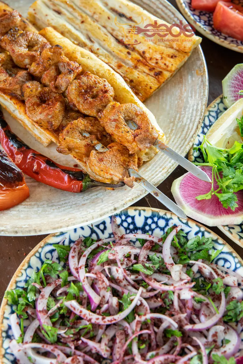 Dede Kebap'ta pide &uuml;zerinde yağlı kara şişleri; her par&ccedil;anın &uuml;st&uuml;nde etin kendi yağı g&ouml;r&uuml;n&uuml;yor